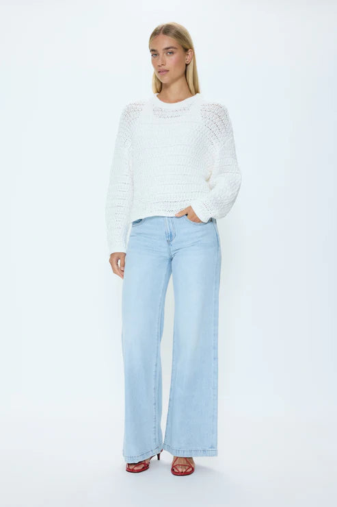 Model wearing white knit crew neck sweater with light blue jeans
