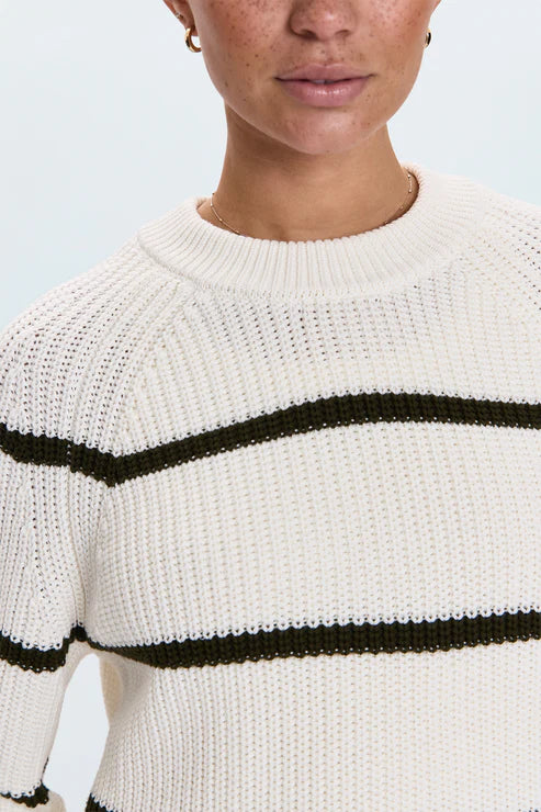 Close-up of white knit sweater with black horizontal stripes and crewneck